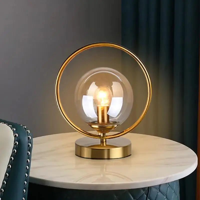 luminária de mesa com esfera de vidro âmbar e anel dourado acesa