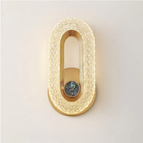 arandela de cristal led oval dourada acesa na parede