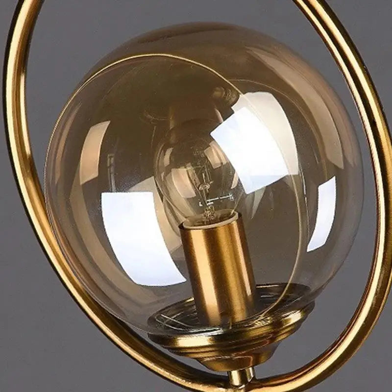 luminária de mesa com esfera de vidro âmbar e anel dourado acesa - foto 3