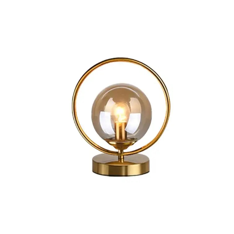 luminária de mesa com esfera de vidro âmbar e anel dourado acesa - foto 5